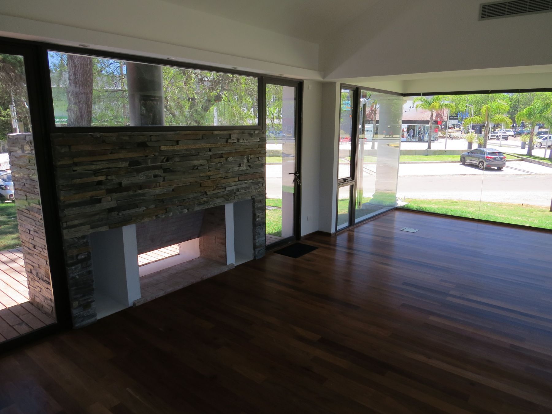 Otra fotografía de la estufa de piedra, el piso de lapacho, con énfasis en el ventanal que apunta hacia la proa.